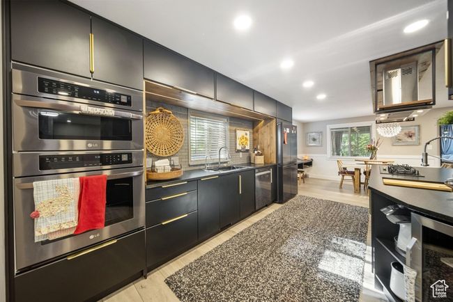 Kitchen with appliances with stainless steel finishes, recessed lighting, wine cooler, light wood-type flooring, and dark countertops | Image 8