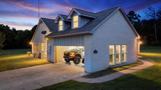 Property exterior at dusk featuring a shingled roof, a yard, a garage, concrete driveway, and brick siding | Image 22