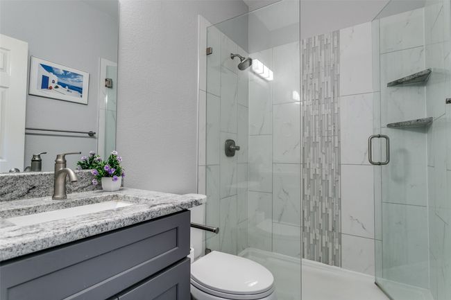 Full bathroom featuring a stall shower, vanity, toilet, and a textured wall | Image 19