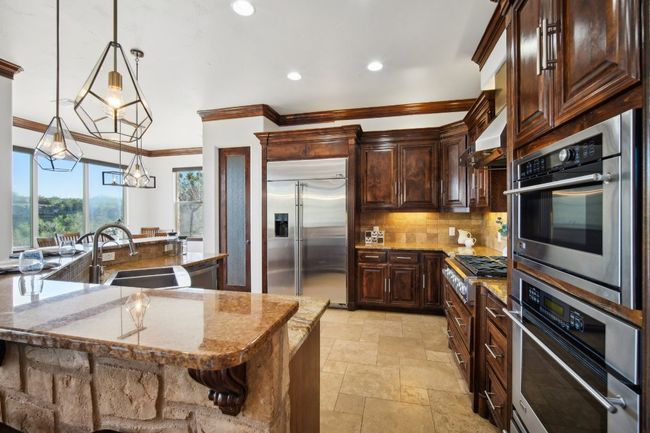 Kitchen featuring range hood, a sink, stone tile flooring, stainless steel appliances, and tasteful backsplash | Image 18