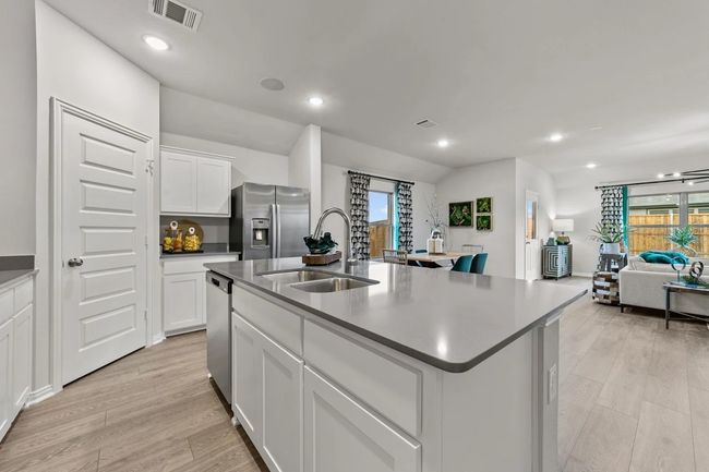 Kitchen featuring stainless steel appliances, a sink, light wood-style flooring, a center island with sink, and white cabinets | Image 23