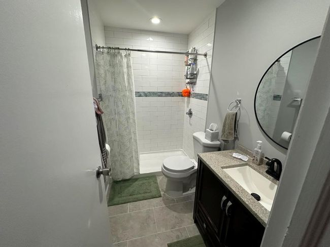 Bathroom with a shower stall, toilet, vanity, and tile patterned floors | Image 5