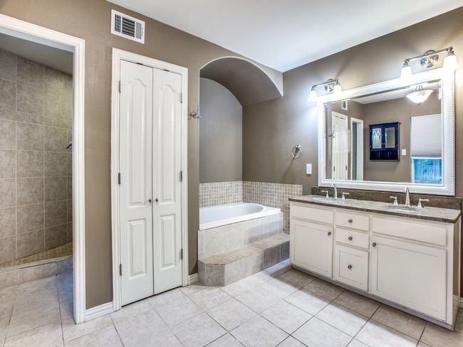 Bathroom with tile patterned flooring, a garden tub, visible vents, and a sink | Image 18