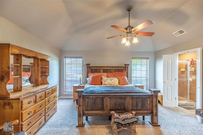 Bedroom featuring lofted ceiling, light carpet, multiple windows, baseboards, and connected bathroom | Image 13