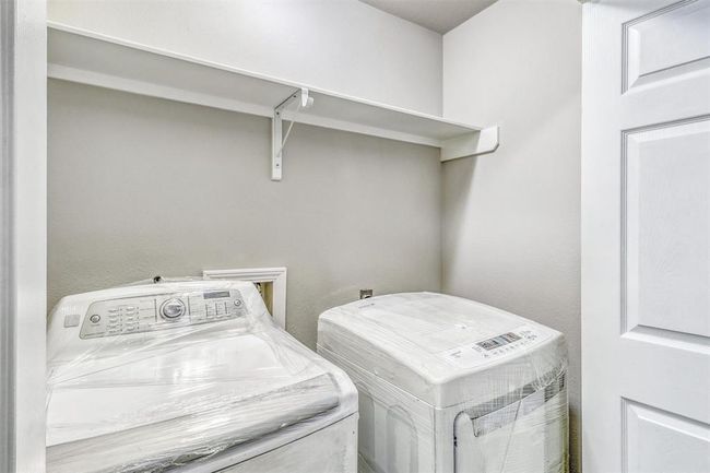 The laundry area is neatly tucked behind double folding doors and features stylish decorator paint along with a full-width shelf that is perfect for keeping supplies organized and within reach. | Image 17