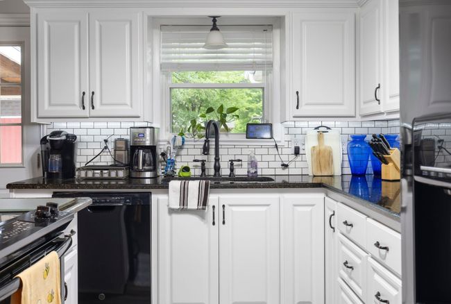 Kitchen featuring black appliances, white cabinets, tasteful backsplash, and dark stone countertops | Image 7