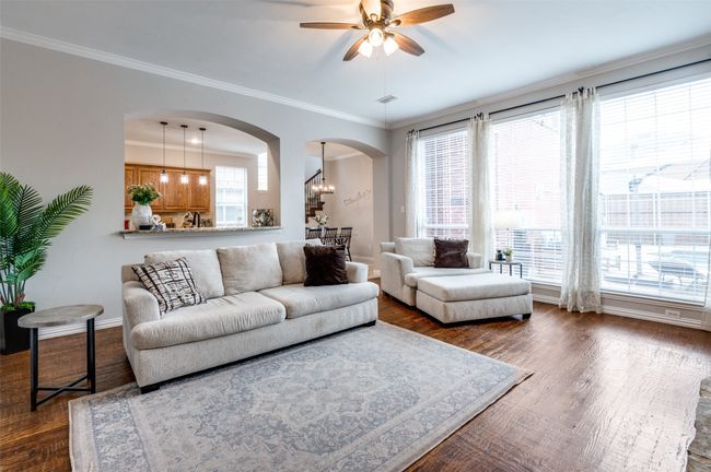 Living room featuring arched walkways, a ceiling fan, hand scraped hardwood finished floors, and crown molding, open to kitchen | Image 40