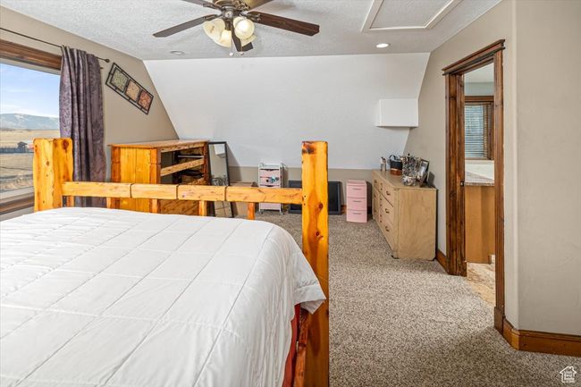 Bedroom featuring ceiling fan, vaulted ceiling, a textured ceiling, and carpet | Image 18