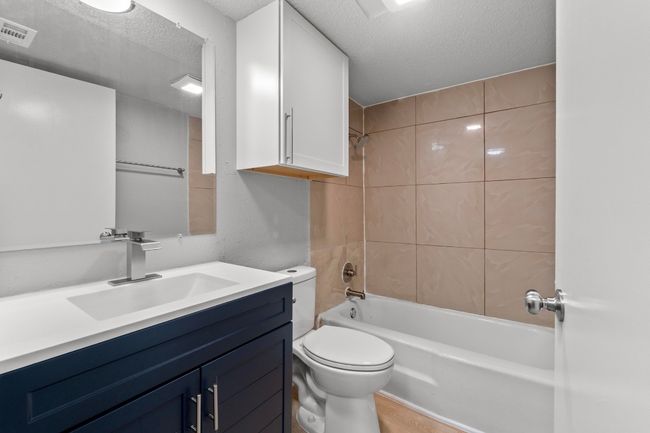 Bathroom with a textured ceiling, vanity, shower combination, toilet, and visible vents | Image 18