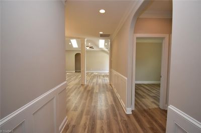 The foyer has wainscoting, double crown molding, luxury vinyl plank flooring, recessed lighting and cased opening leading to guest bedrooms. Another finished home pictured. Actual home is still under construction. | Image 2