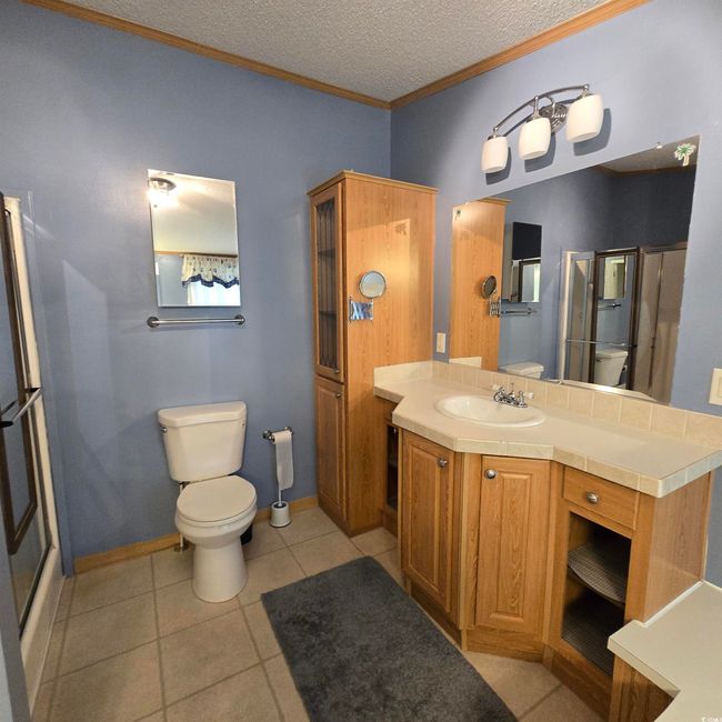 Full bathroom featuring ornamental molding, tile patterned flooring, a textured ceiling, vanity, and a shower stall | Image 25