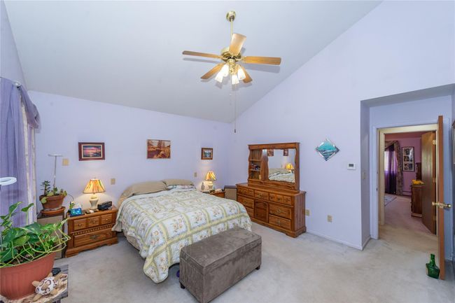 Bedroom with ceiling fan, high vaulted ceiling, baseboards, and light colored carpet | Image 27