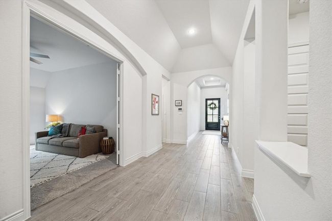 The entry hallway sets a tone of elevated elegance with beautiful wood-look tile floors and a soaring coffered ceiling, creating a grand and inviting first impression. This view offers a reverse angle looking back toward the front entry, highlighting the graceful flow of the space. | Image 6