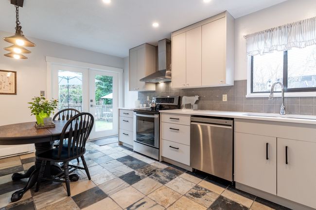 Kitchen with tasteful backsplash, wall chimney range hood, light countertops, appliances with stainless steel finishes, and a sink | Image 5