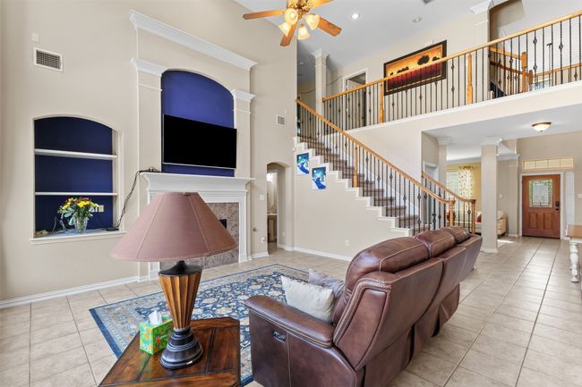 Tiled living area featuring a towering ceiling, stairs, a ceiling fan, ornate columns, and baseboards | Image 13
