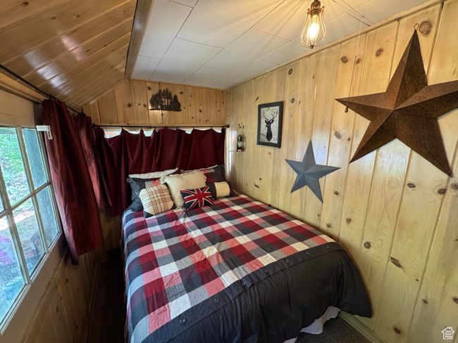 Bedroom featuring wood walls, vaulted ceiling, and carpet | Image 7