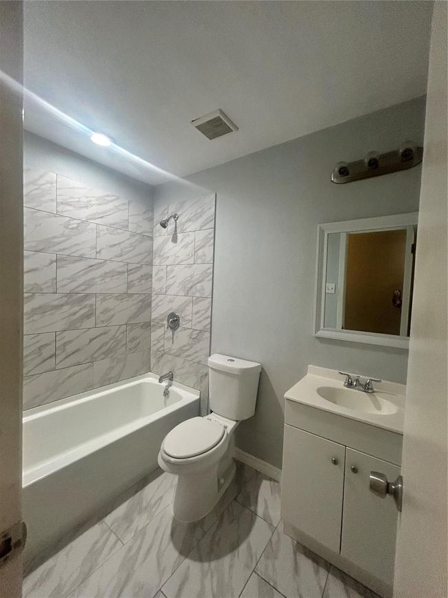 Full bath featuring marble finish flooring, toilet, vanity, and shower / washtub combination | Image 17