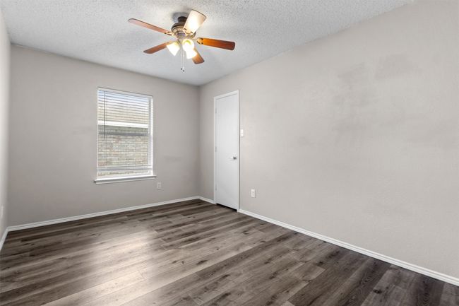 Empty room featuring ceiling fan, dark wood-type flooring, a textured ceiling, and baseboards | Image 23