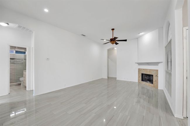 Unfurnished living room with ceiling fan, light tile floors, and a fireplace | Image 11