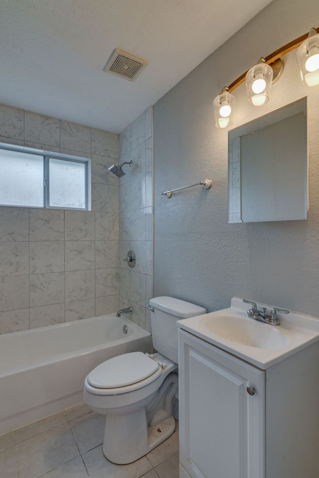 Bathroom featuring tile patterned floors, toilet, shower / bathing tub combination, vanity, and visible vents | Image 17