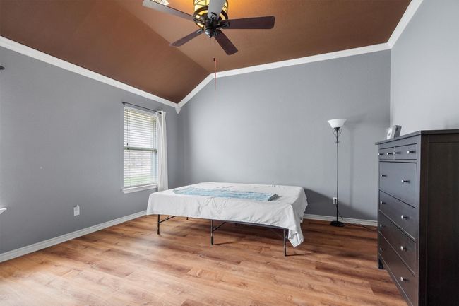 Bedroom with ornamental molding, wood finished floors, lofted ceiling, and ceiling fan | Image 23