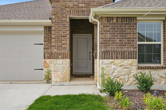 Entrance to property with a shingled roof, stone siding, a garage, brick siding, and driveway | Image 4