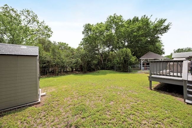 View of yard featuring a storage shed, an outbuilding, a wooden deck, and a fenced backyard | Image 32