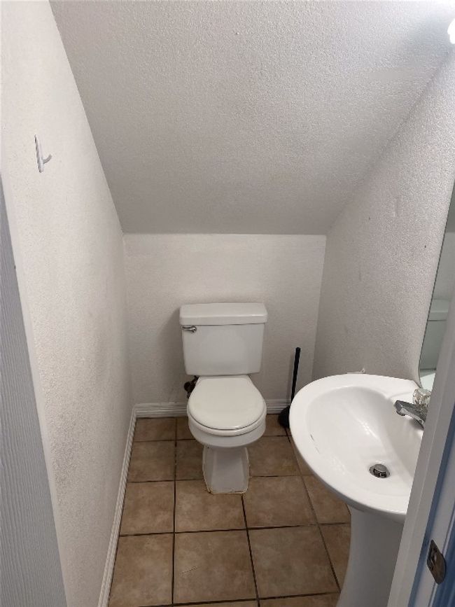 Half bathroom with toilet, baseboards, a textured ceiling, tile patterned floors, and a sink | Image 6