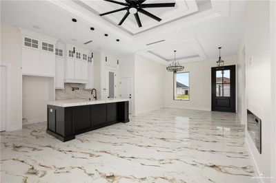 Kitchen with a tray ceiling, a large island, pendant lighting, and white cabinets | Image 3