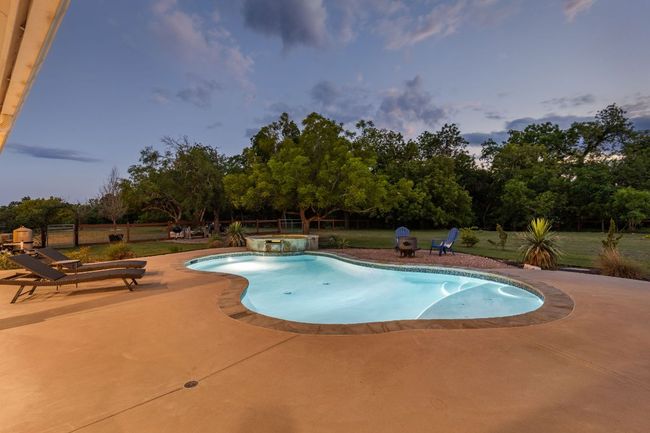 Surrounded by mature oak trees, the pool area provides a serene setting for relaxation and leisure. | Image 35