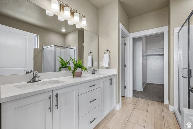 Bathroom featuring double vanity, a spacious closet, a shower stall, and a sink | Image 16