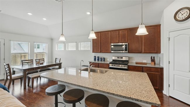 Kitchen featuring stainless steel appliances, lofted ceiling, dark wood-style flooring, decorative backsplash, and a breakfast bar | Image 16