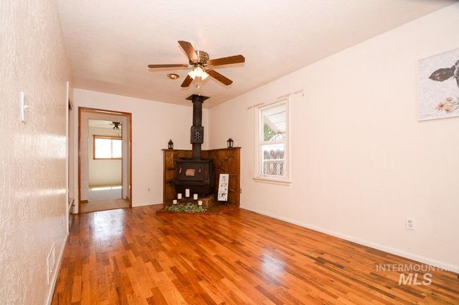 Unfurnished living room with wood finished floors, a ceiling fan, and a wood stove | Image 19
