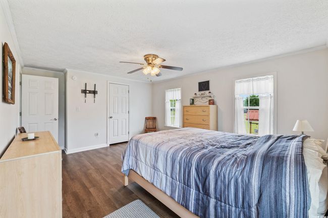 Bedroom with light wood-type flooring, ornamental molding, a textured ceiling, and a ceiling fan | Image 24
