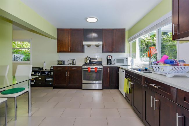 Kitchen featuring white appliances, under cabinet range hood, a sink, and plenty of natural light | Image 29