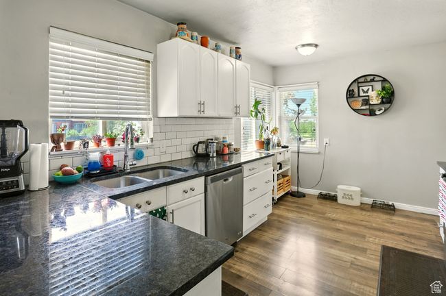 Kitchen with stainless steel dishwasher, white cabinets, backsplash, and dark wood-type flooring | Image 8