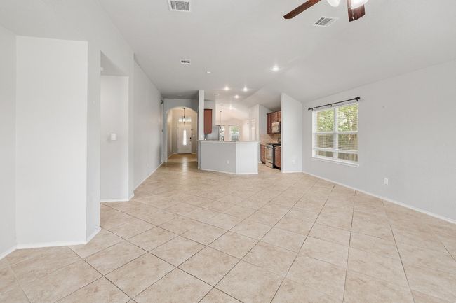Unfurnished living room with light tile patterned flooring, a ceiling fan, lofted ceiling, and arched walkways | Image 6