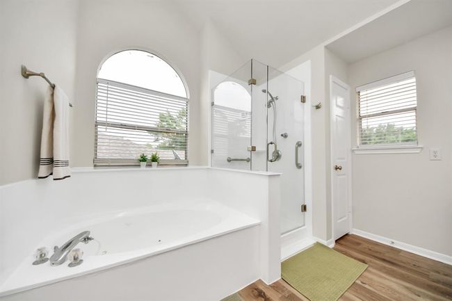 This gorgeous ensuite bathroom showcases a mud-set shower with frameless glass for a sleek, modern touch and effortless access. Natural light pours in through the windows, filling the space with warmth, while the elegant soaking tub offers the perfect spot to unwind and relax. | Image 30