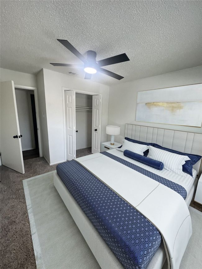 Carpeted bedroom with a textured ceiling, a closet, and ceiling fan | Image 7