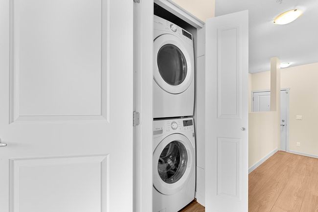 Laundry area with laundry area, light wood-style flooring, stacked washer and clothes dryer, and baseboards | Image 19