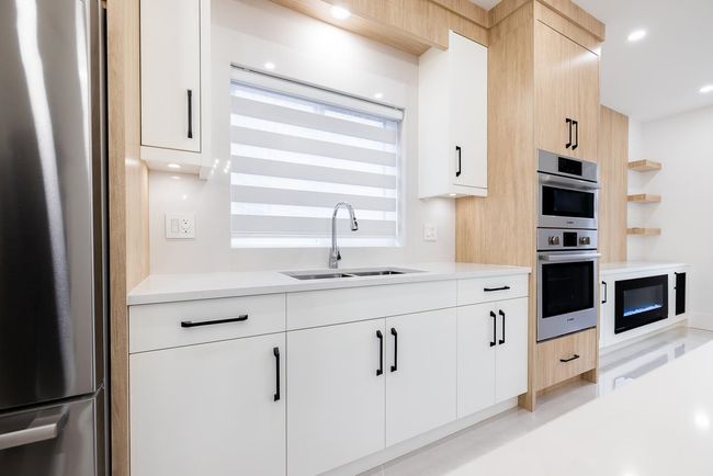 Kitchen featuring stainless steel appliances, light countertops, recessed lighting, white cabinets, and modern cabinets | Image 17