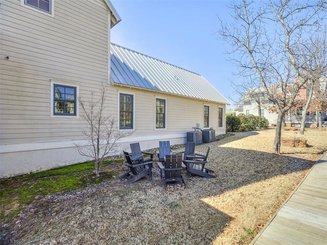 Back of house with a fire pit, metal roof, and central AC | Image 29