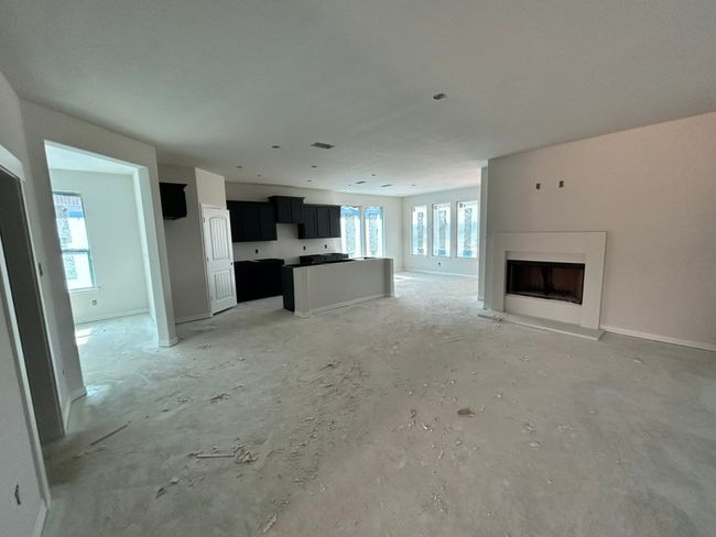 Unfurnished living room featuring a fireplace with raised hearth and baseboards | Image 4
