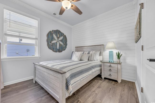 Bedroom with baseboards, wood finished floors, ornamental molding, wooden walls, and a ceiling fan | Image 23