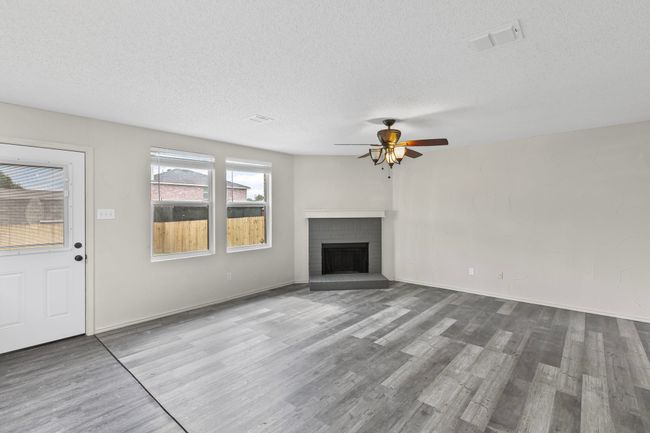 Unfurnished living room with wood finished floors, a ceiling fan, a textured ceiling, and a fireplace | Image 4