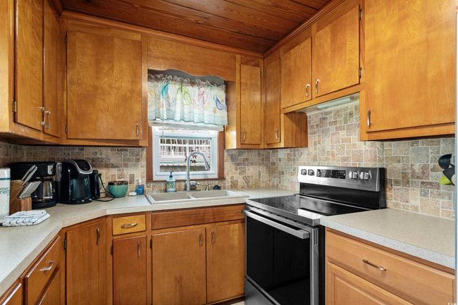 Kitchen with stainless steel electric range oven, a sink, tasteful backsplash, light countertops, and wood ceiling | Image 33