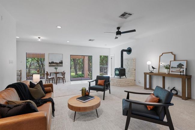Living room with light carpet, visible vents, and a wood stove | Image 7
