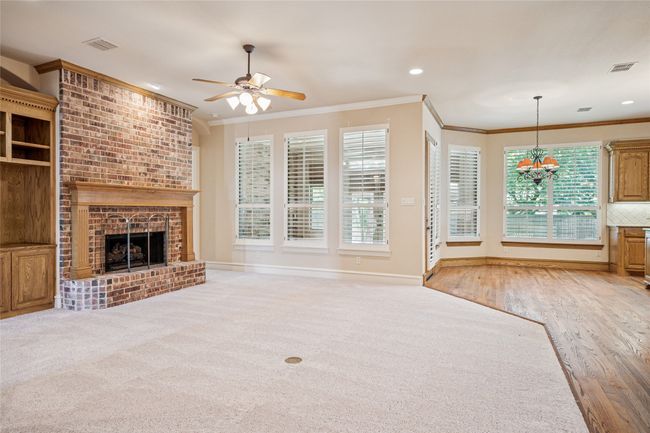 Living room with a brick fireplace and built in cabinets adjoining the open kitchen and breakfast nook. | Image 6