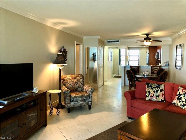 Living room with visible vents, crown molding, light tile patterned floors, baseboards, and ceiling fan | Image 11