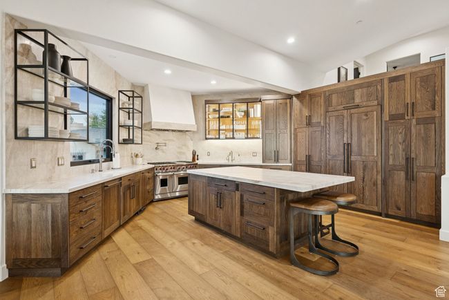Kitchen with premium range hood, stainless steel appliances, a center island, light wood-style floors, and decorative backsplash | Image 23